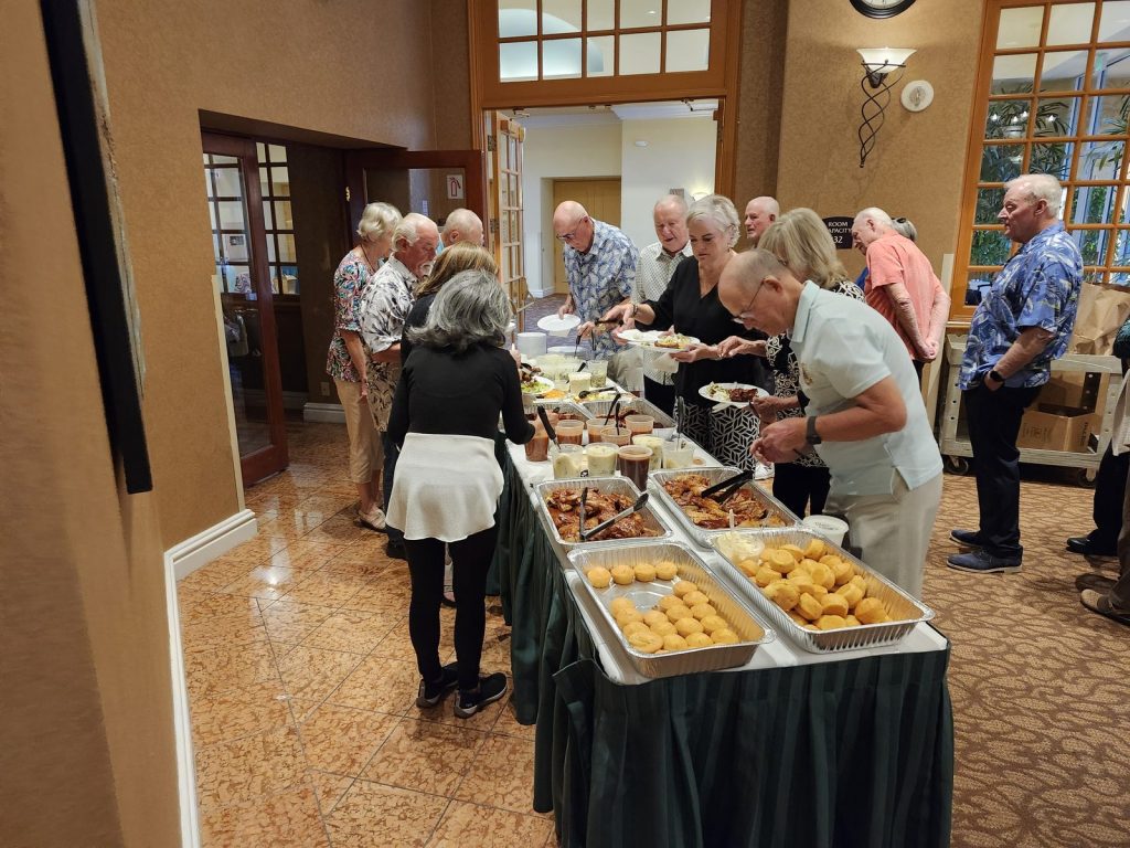 Members serving themselves at a buffet during a club social
