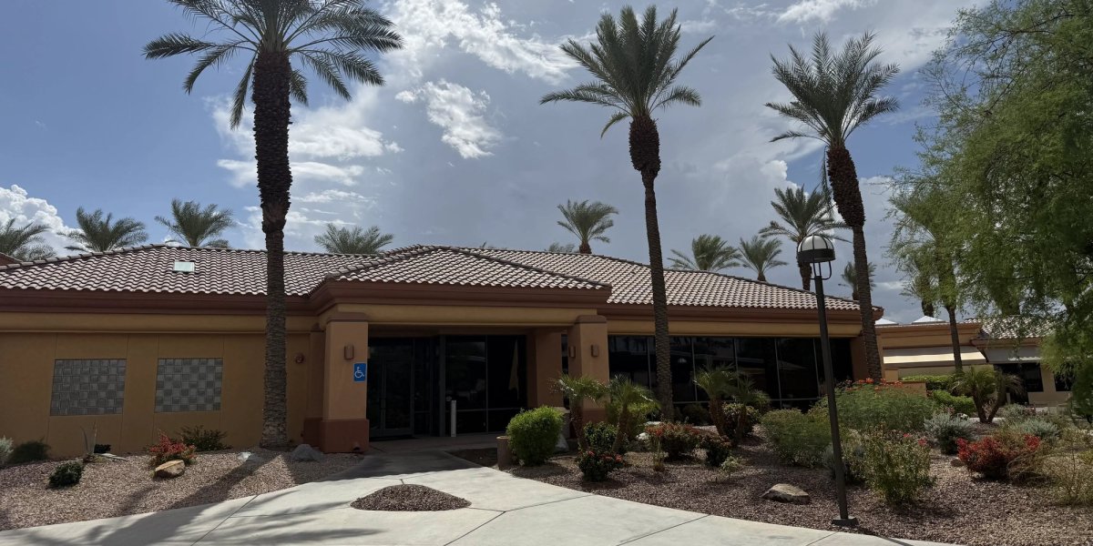 The clubhouse that is home to the billiards hall, with palm trees and desert landscaping