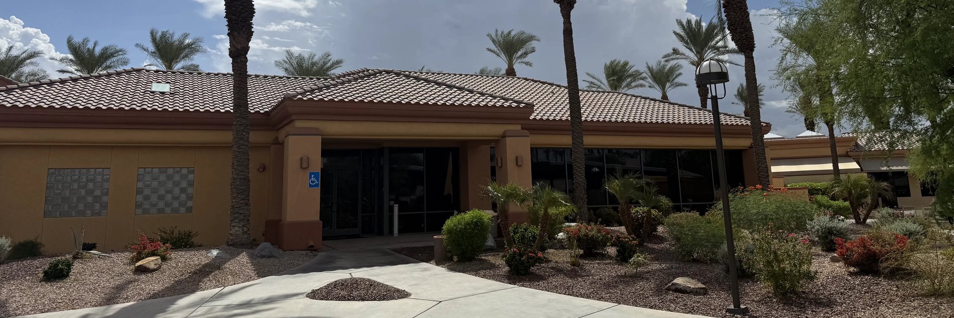 The clubhouse that is home to the billiards hall, with palm trees and desert landscaping