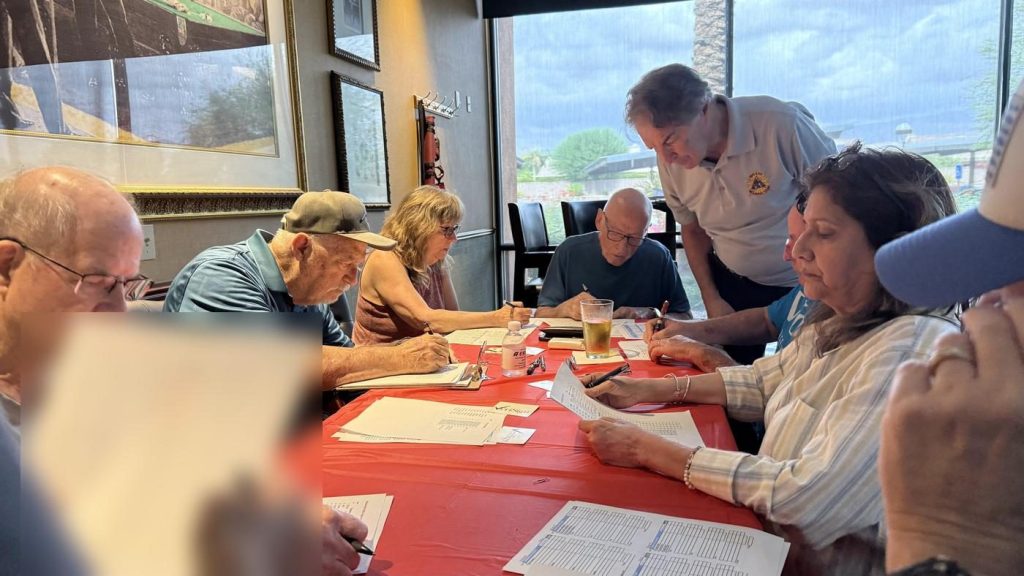 Members filling out sheets at a table during Wednesday Night League draft night