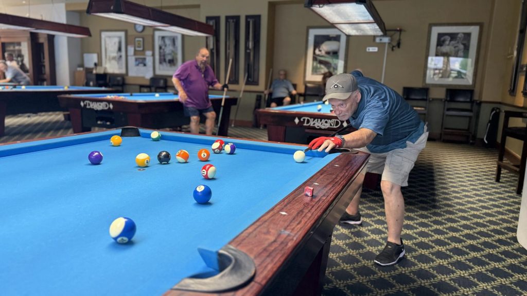 A member in a red glove shoots along the rail while another player waits nearby